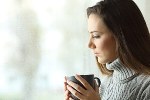 A woman drinks coffee and thinks about how her brother needs one of the best treatment programs for addiction